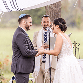 bride and groom standing in front of a rabbi